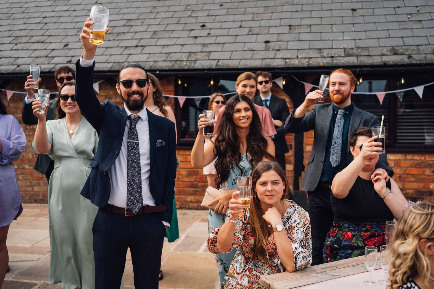 Wedding guests raise their glasses in celebration during an outdoor reception.