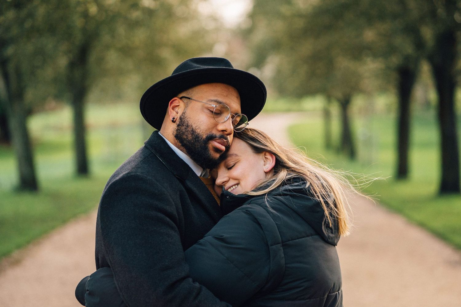 An intimate moment captured between a couple on a tree-lined pathway.