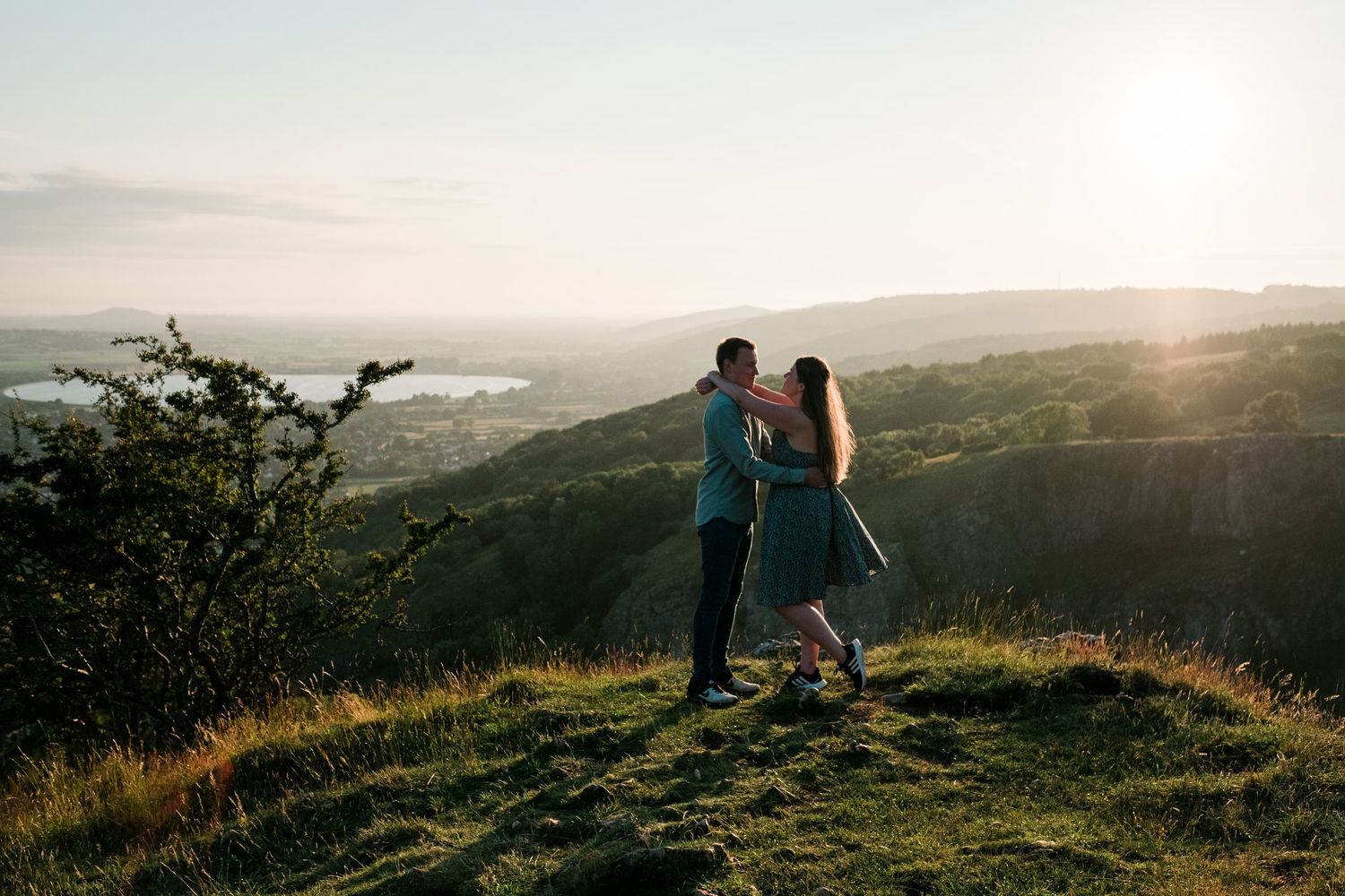 Silhouettes of people walking along a hilltop trail during golden sunset hour.