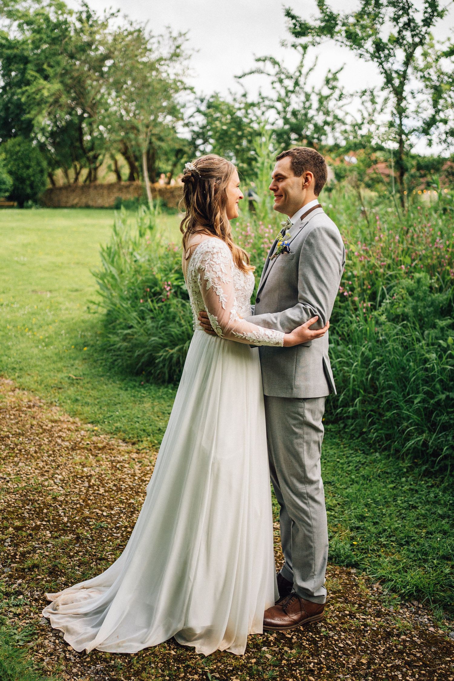 Wedding couple sharing a moment together on a garden path surrounded by greenery.