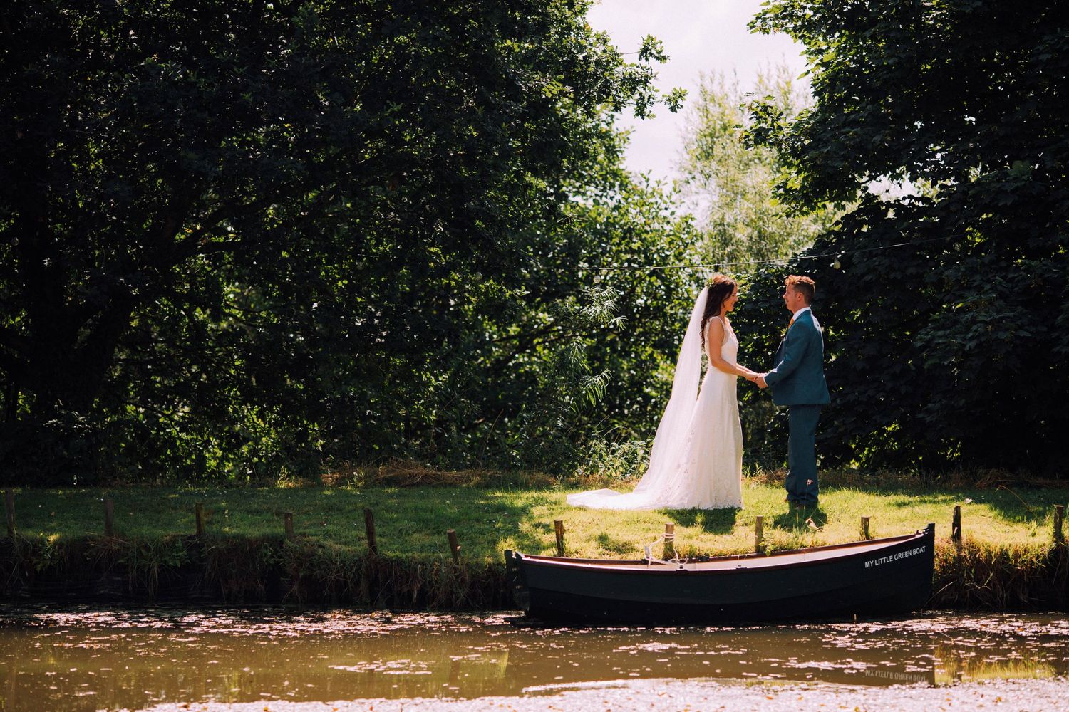 Wedding couple strolling along tree-lined path during outdoor celebration.