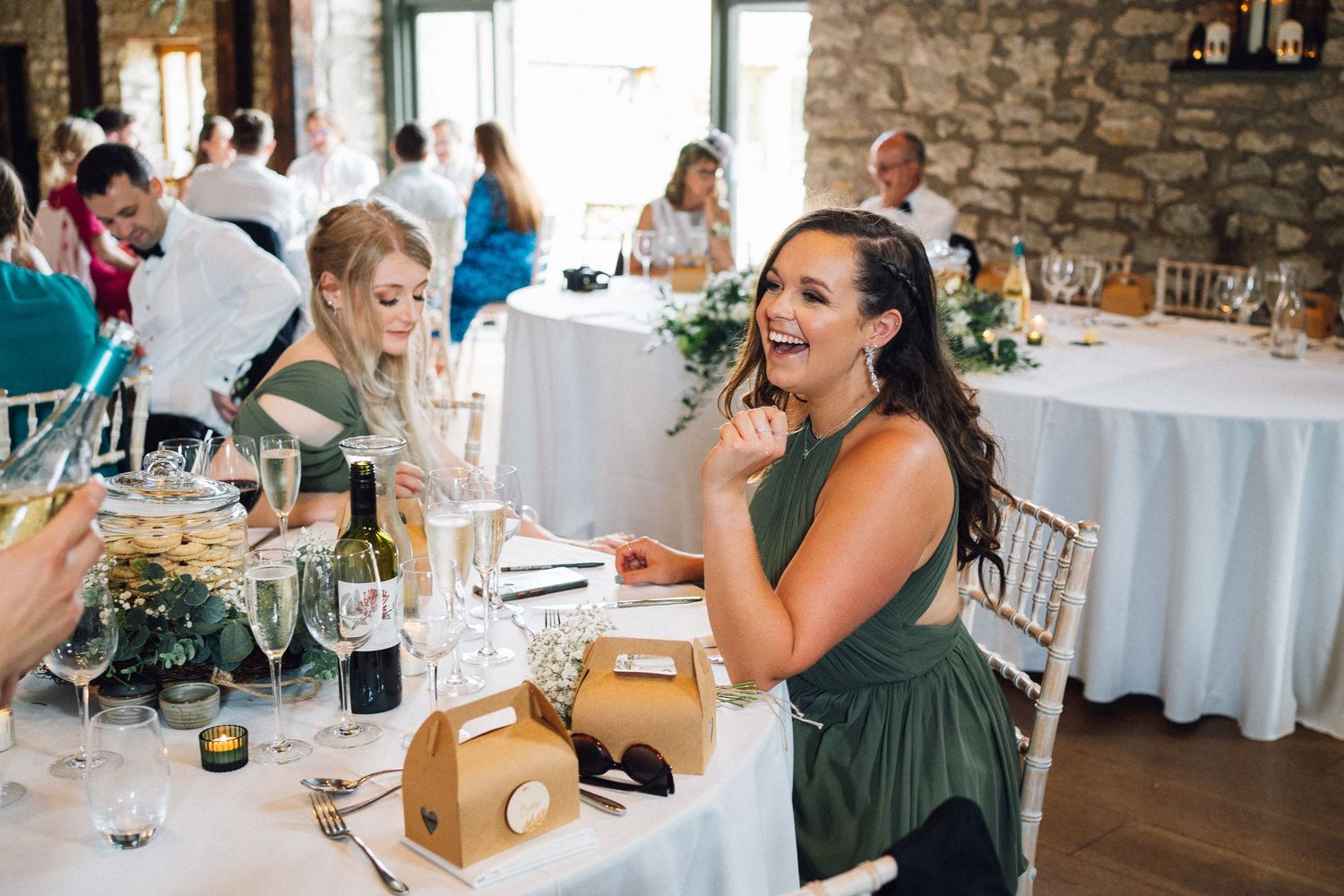 Wedding reception guests enjoying dinner and conversation in a rustic stone venue.