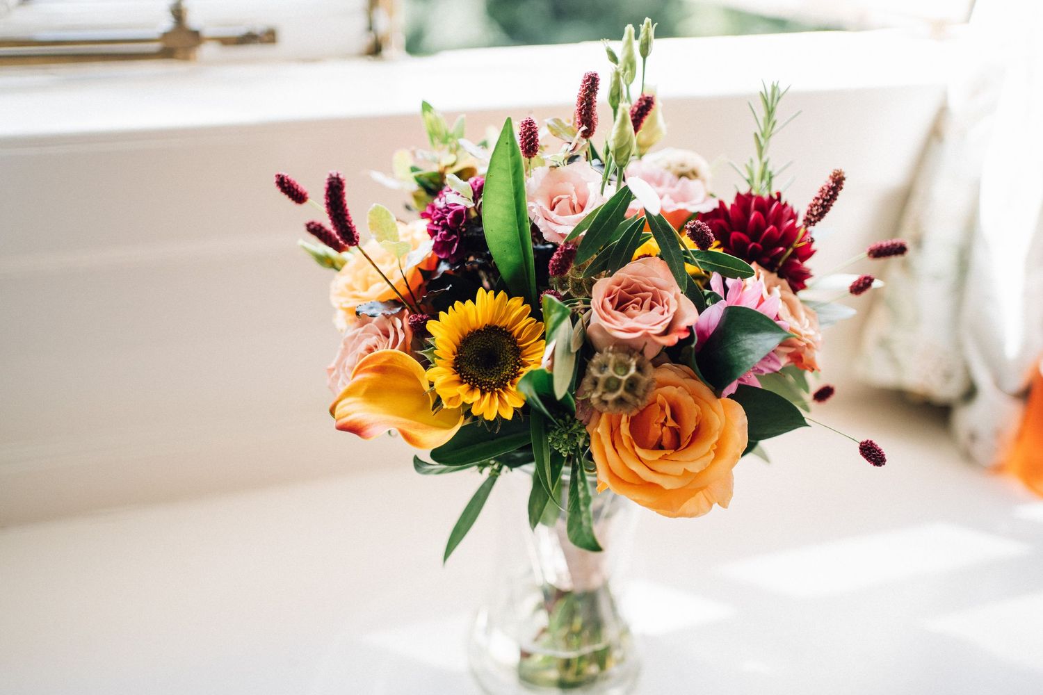 Colorful floral arrangements with sunflowers and roses displayed in glass vases.