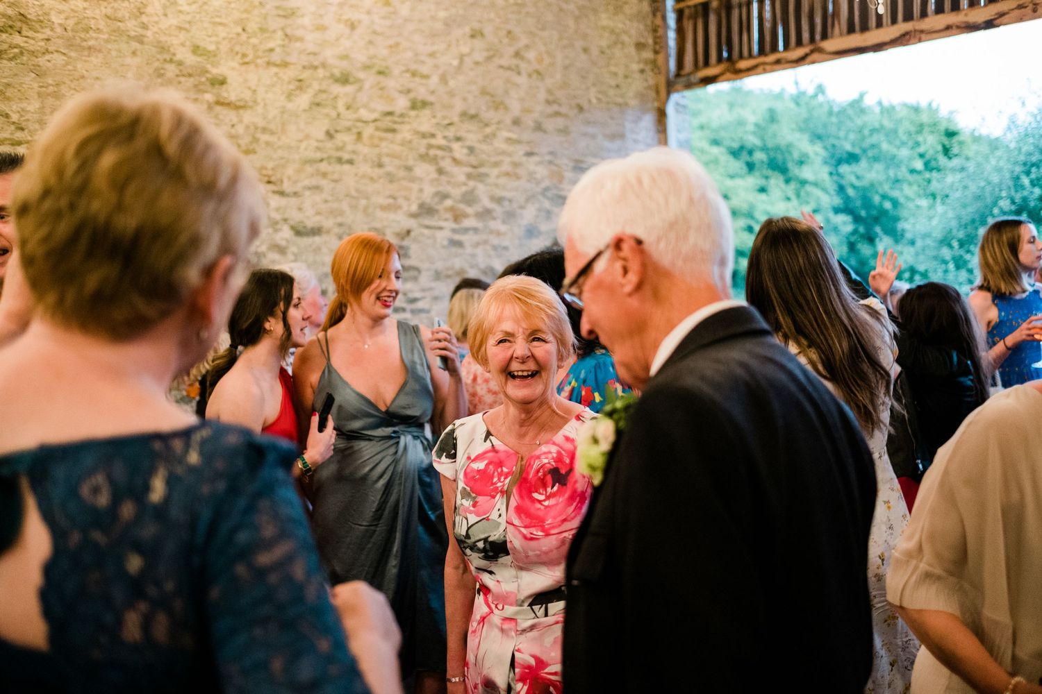 Lively wedding reception with guests dancing and laughing in a rustic stone venue.