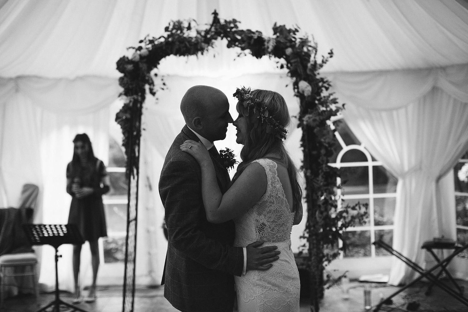 A romantic black and white moment under a floral arch at a wedding reception.