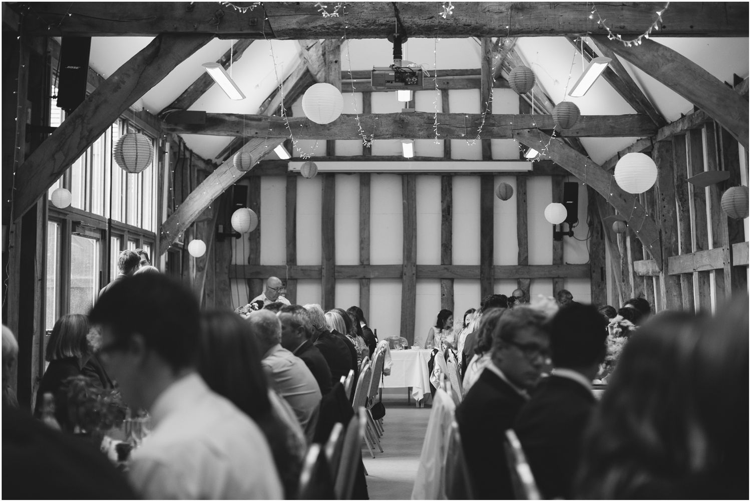 Rustic barn wedding venue with exposed wooden beams and string lights.