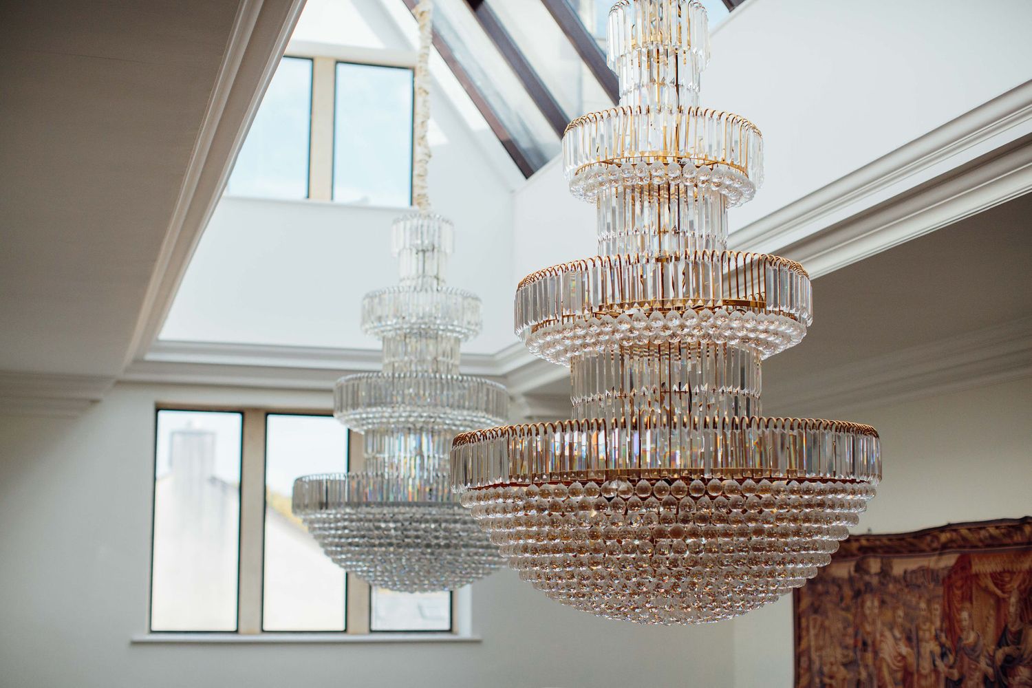 Crystal chandelier hanging from a vaulted ceiling with skylights.
