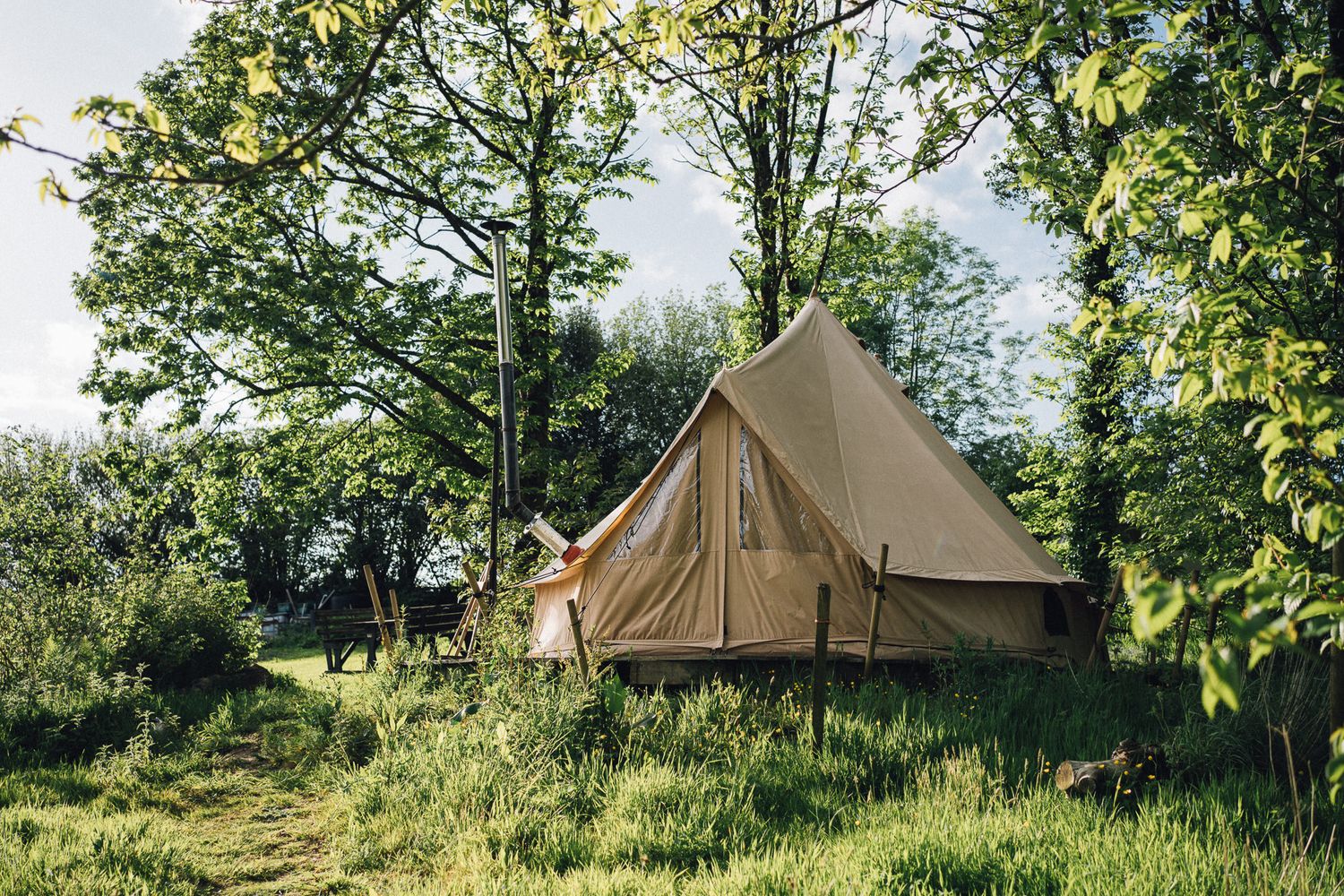 Bell tents set up in a green field for glamping at a wedding venue.