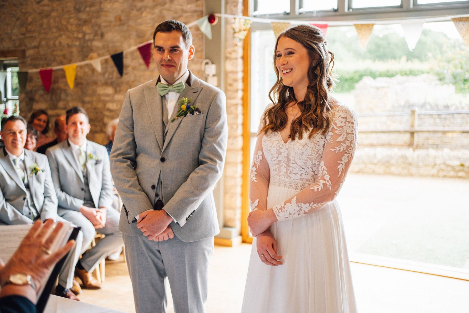 Wedding party members share joyful reactions and laughter during candid moments at an indoor venue.
