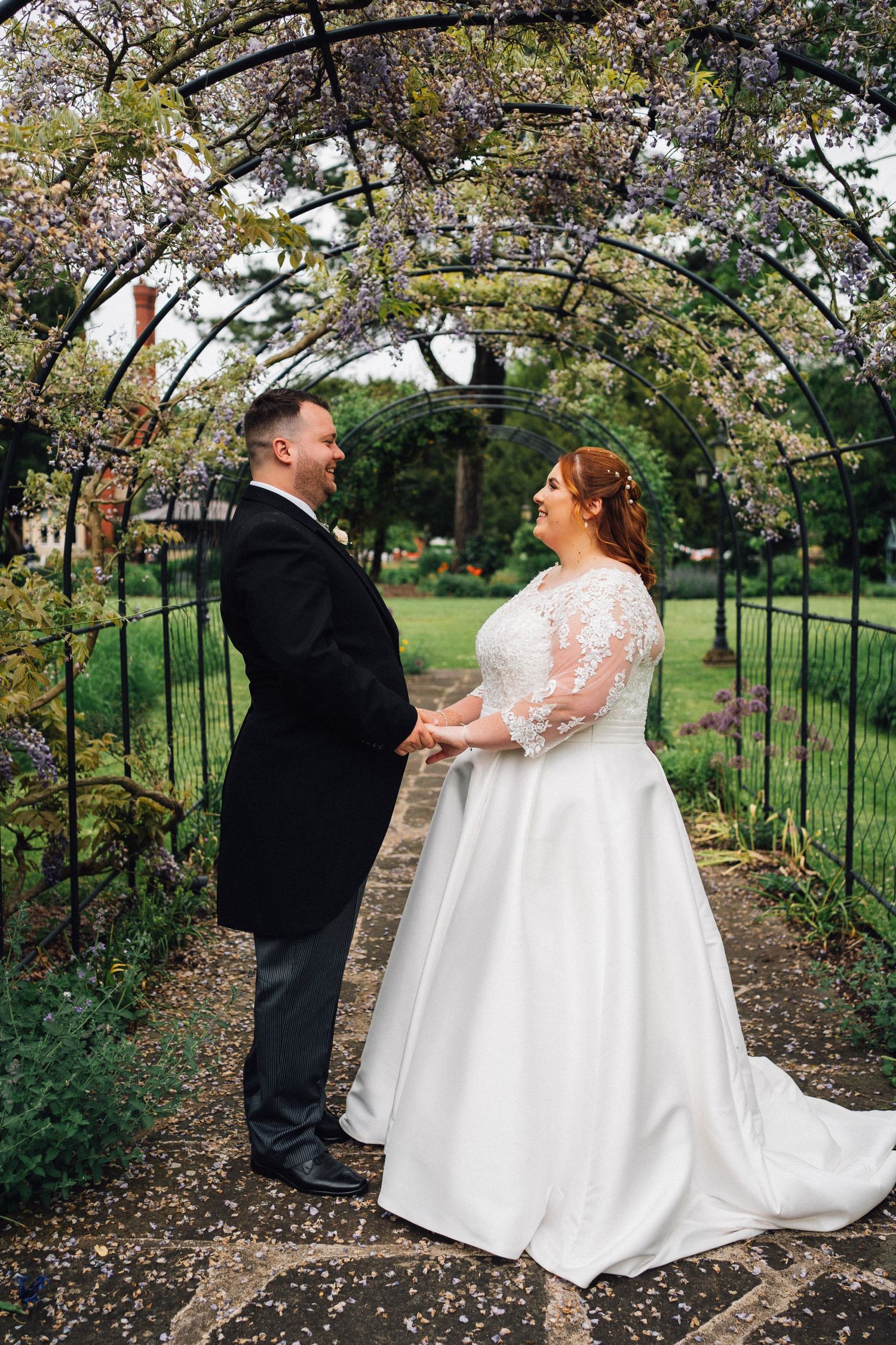 A romantic moment captured under blooming cherry blossom trees in a garden archway.