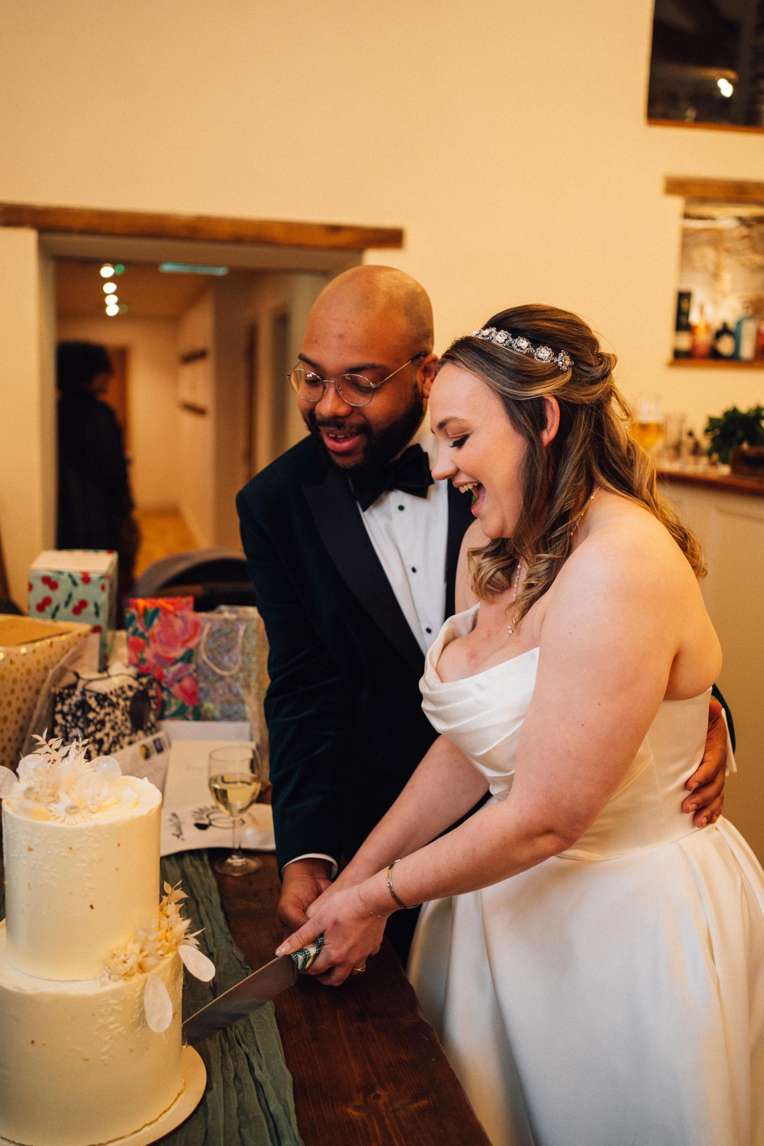 A couple cuts their elegant white wedding cake together during their reception celebration.