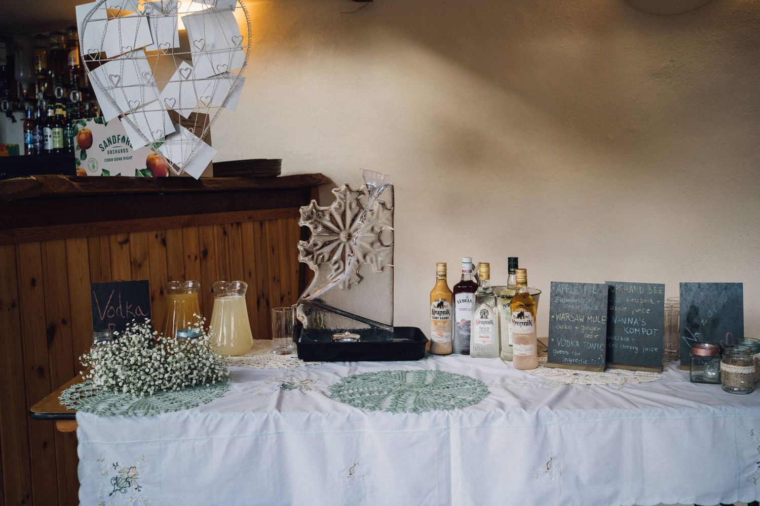 Wedding reception bar area decorated with lace tablecloths and delicate flowers.