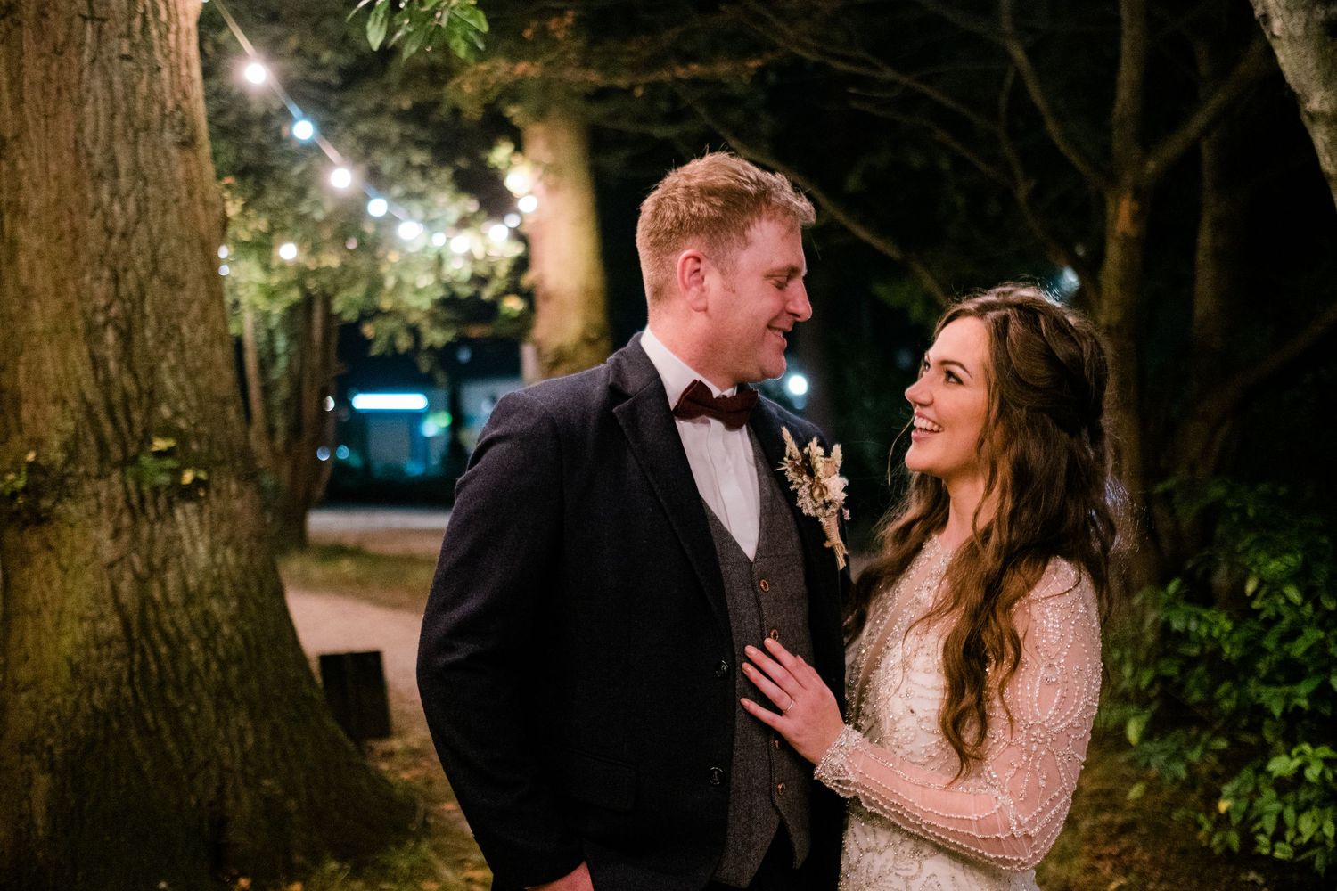 Intimate wedding photos captured under trees with twinkling lights.