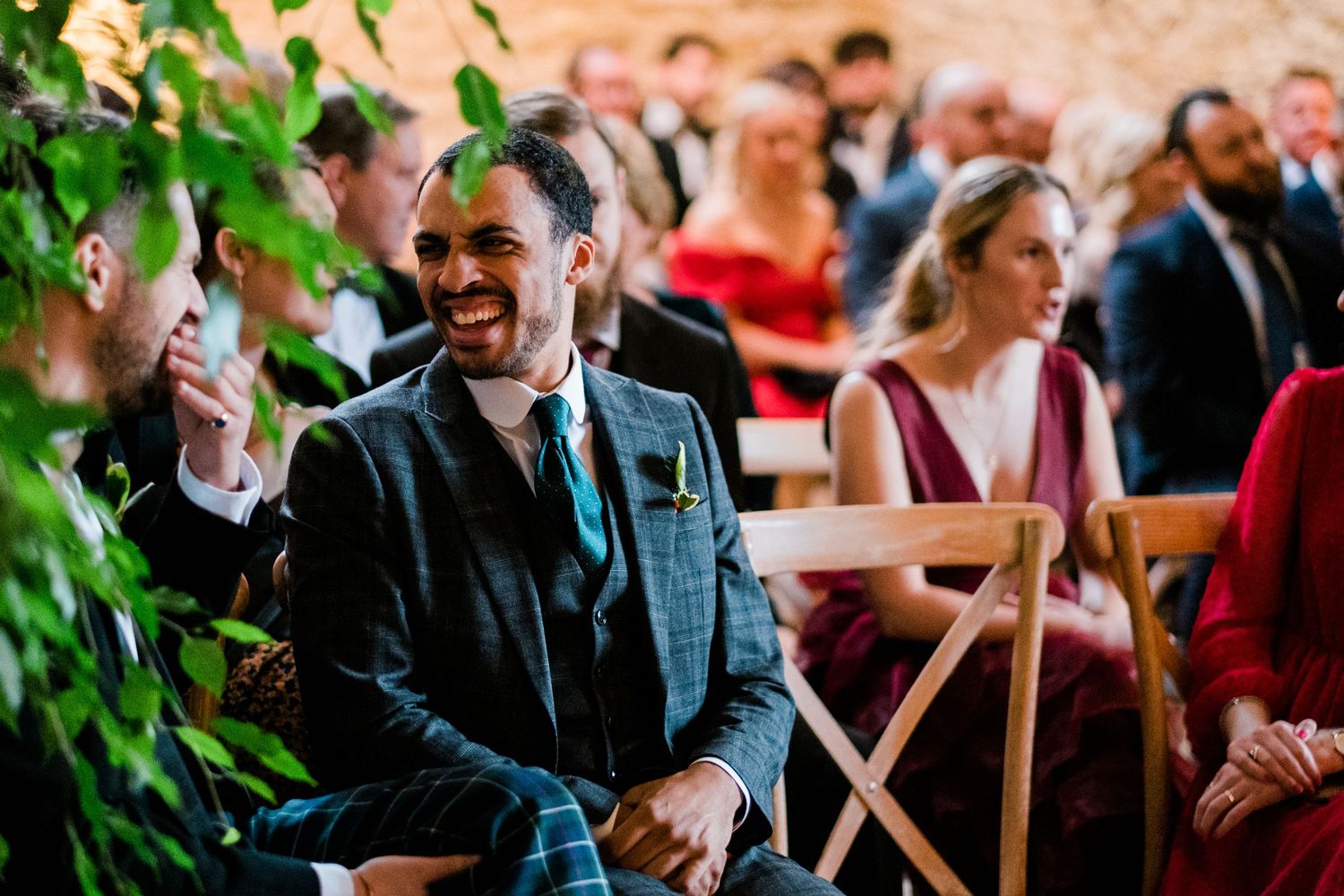 Wedding party members laughing together during a reception in an elegant stone venue.