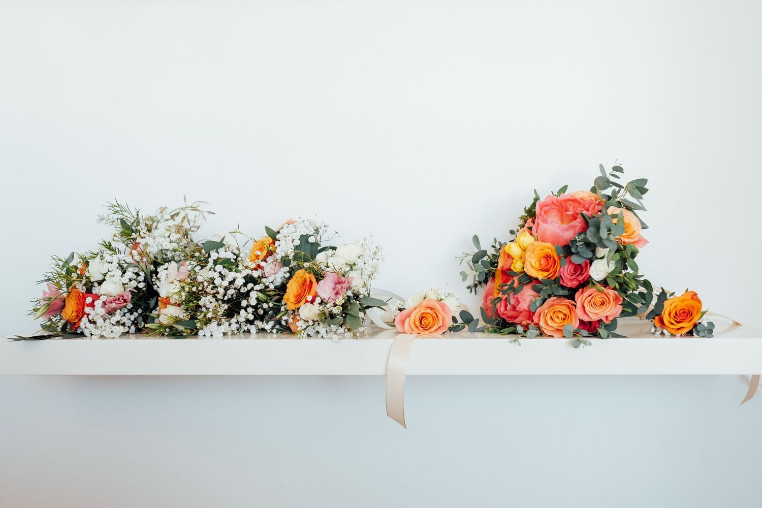 Delicate floral arrangement with roses and greenery on white background.