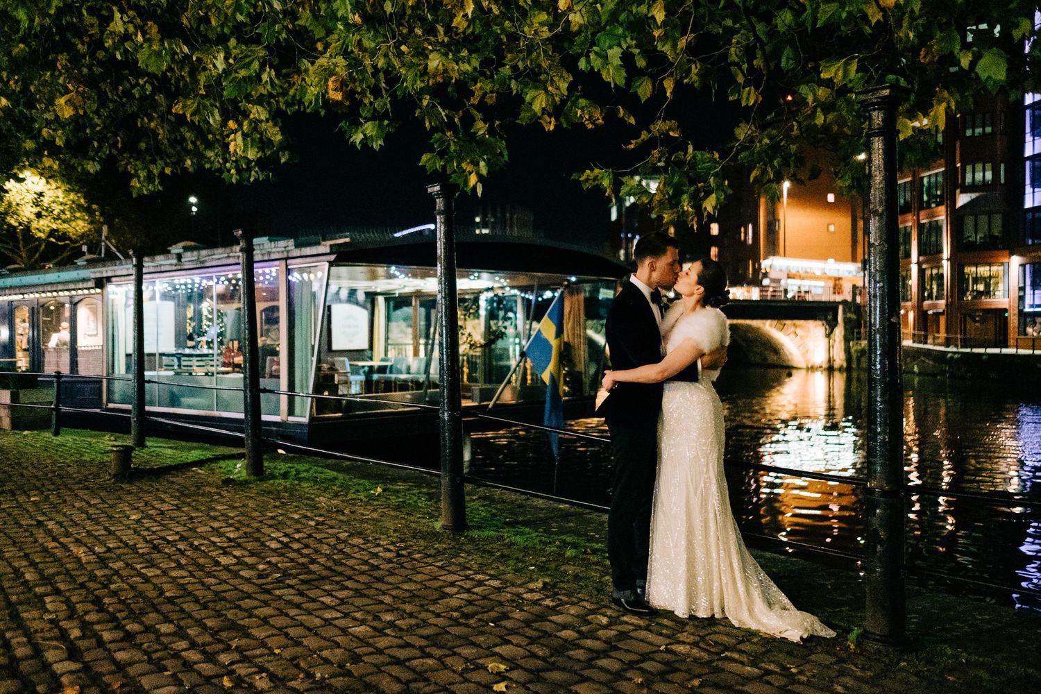 A couple shares a romantic moment by illuminated city docks at night.