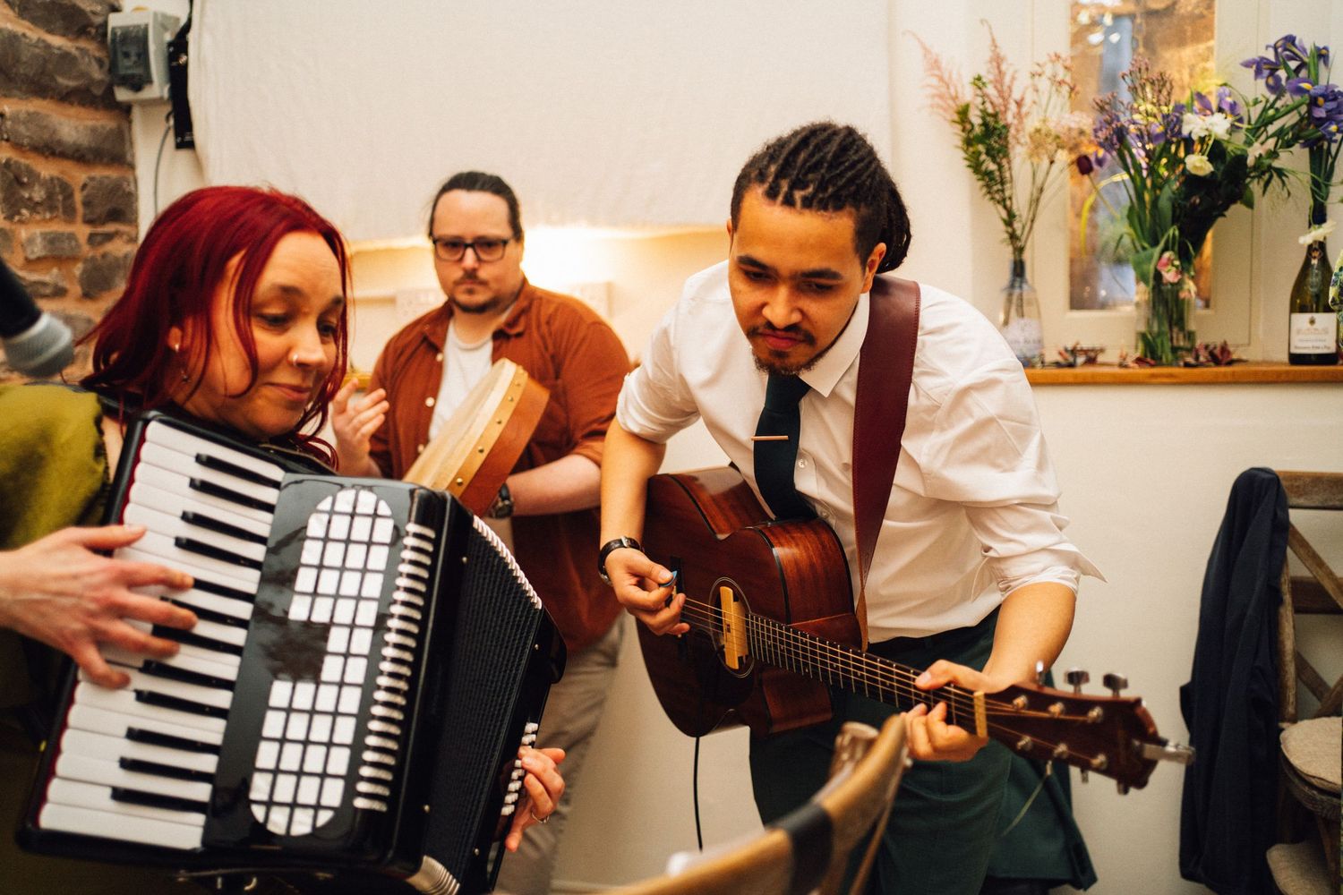 Musicians perform at a wedding reception with an accordion and acoustic guitar.