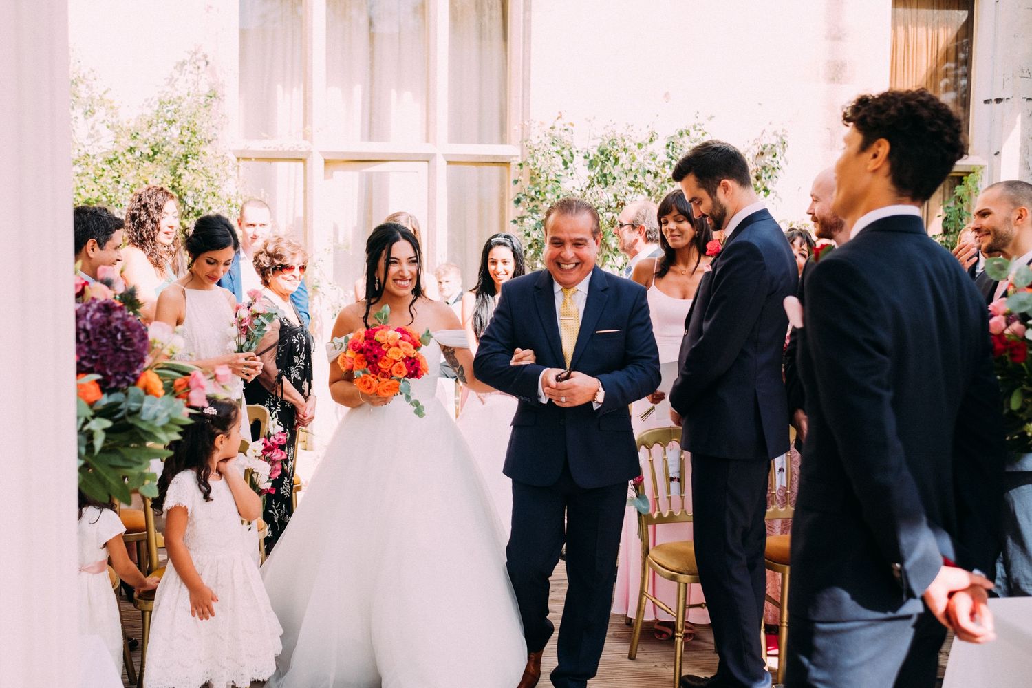 Wedding celebration with guests mingling in a bright, columned reception space.