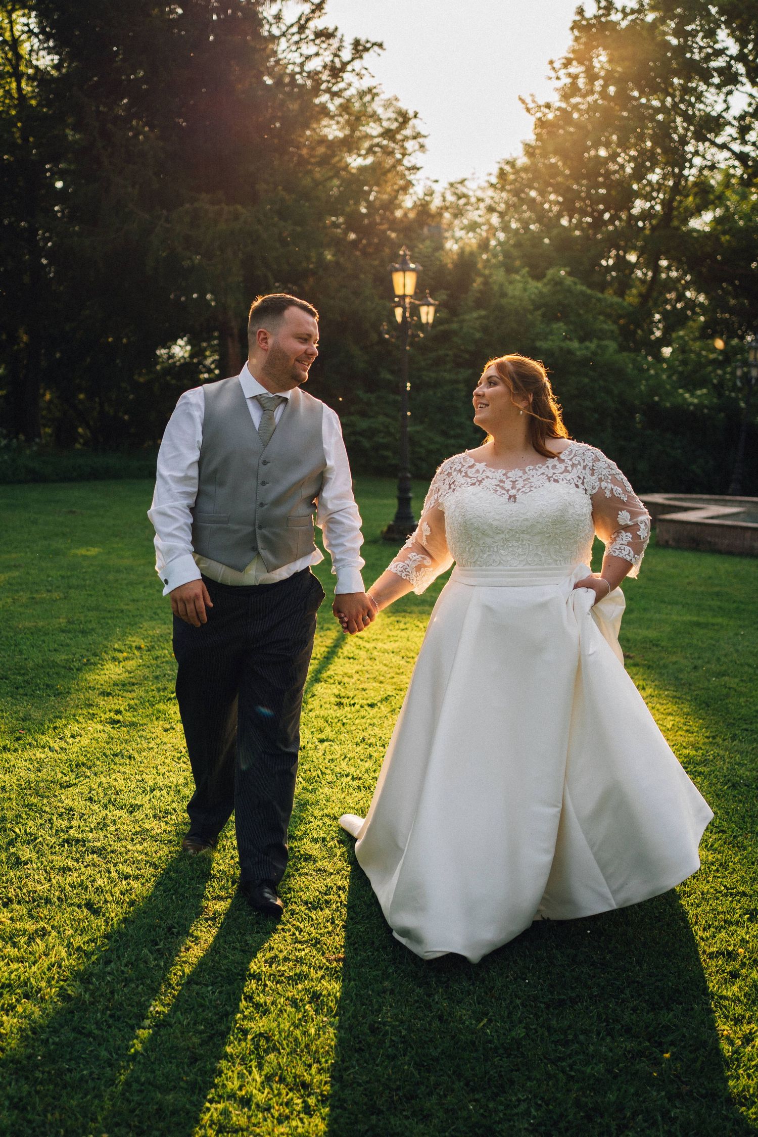 Couple dances playfully on grass during golden hour wedding photoshoot.