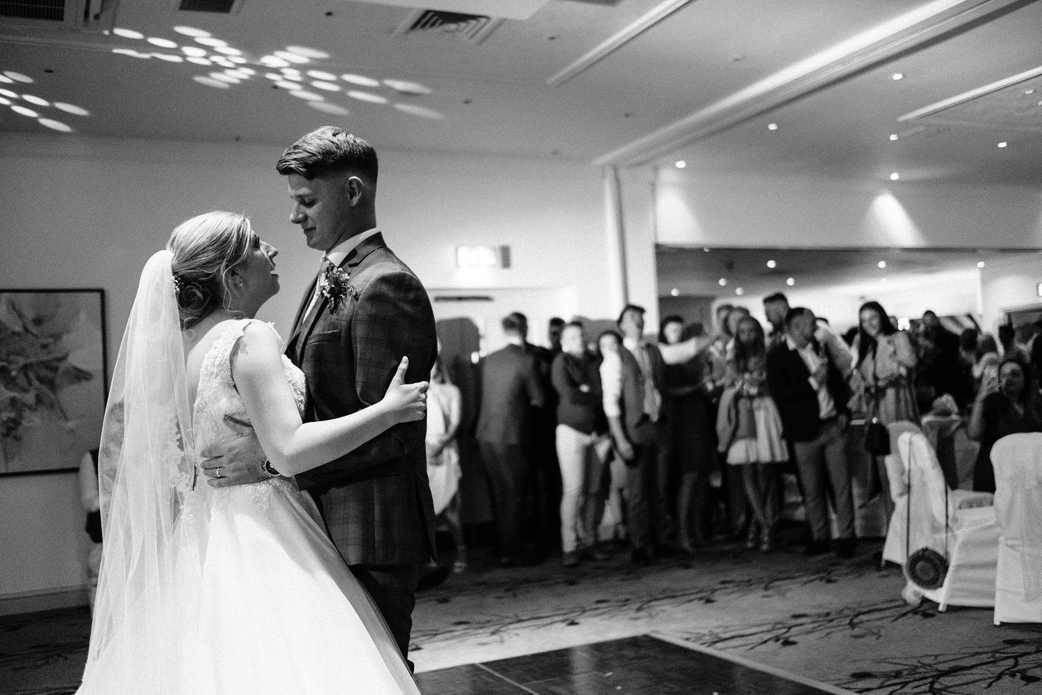 Wedding reception dance floor filled with guests celebrating under ambient lighting.