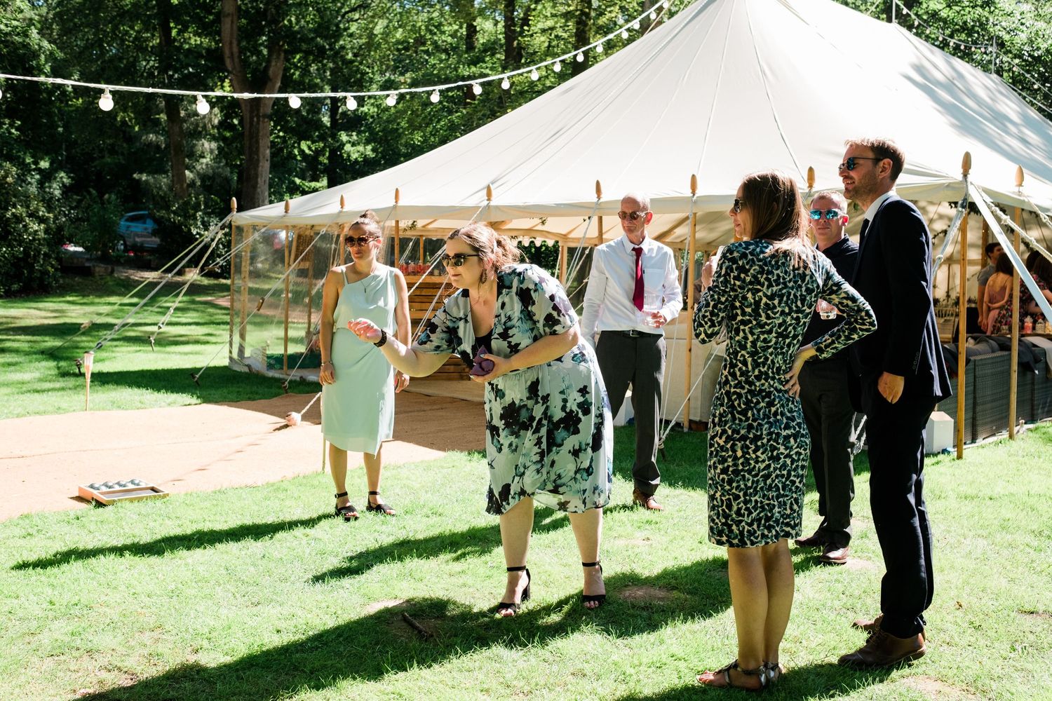 Wedding reception tent setup on a sunny day with guests mingling outside.