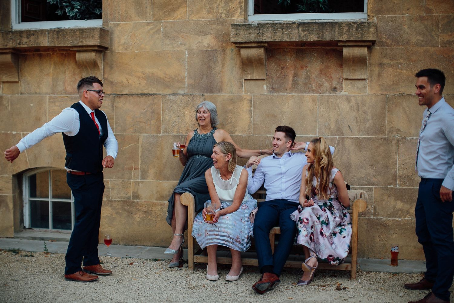 Wedding guests relaxing on stone steps outside a historic building.