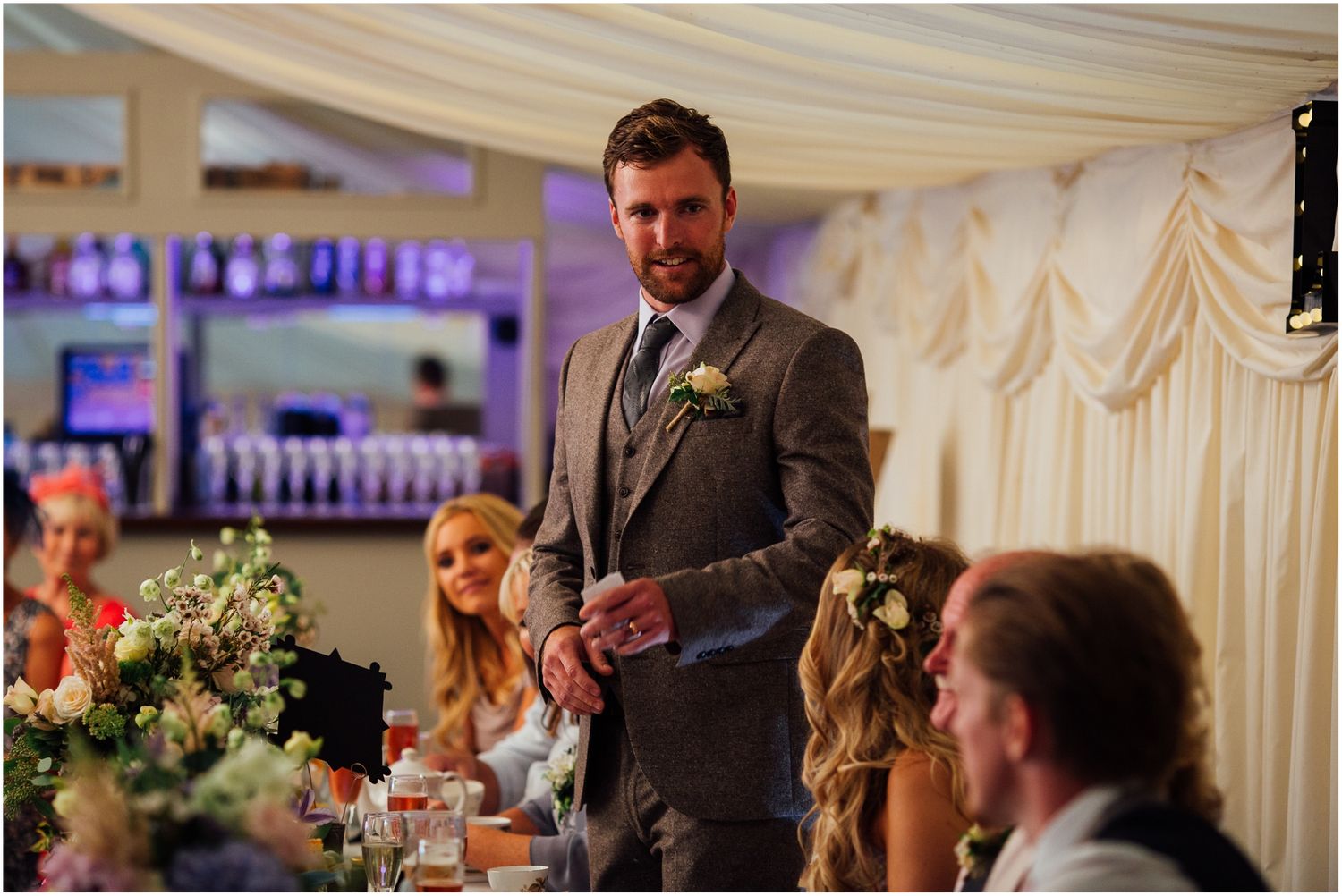 Wedding reception speeches being given under a white marquee tent.