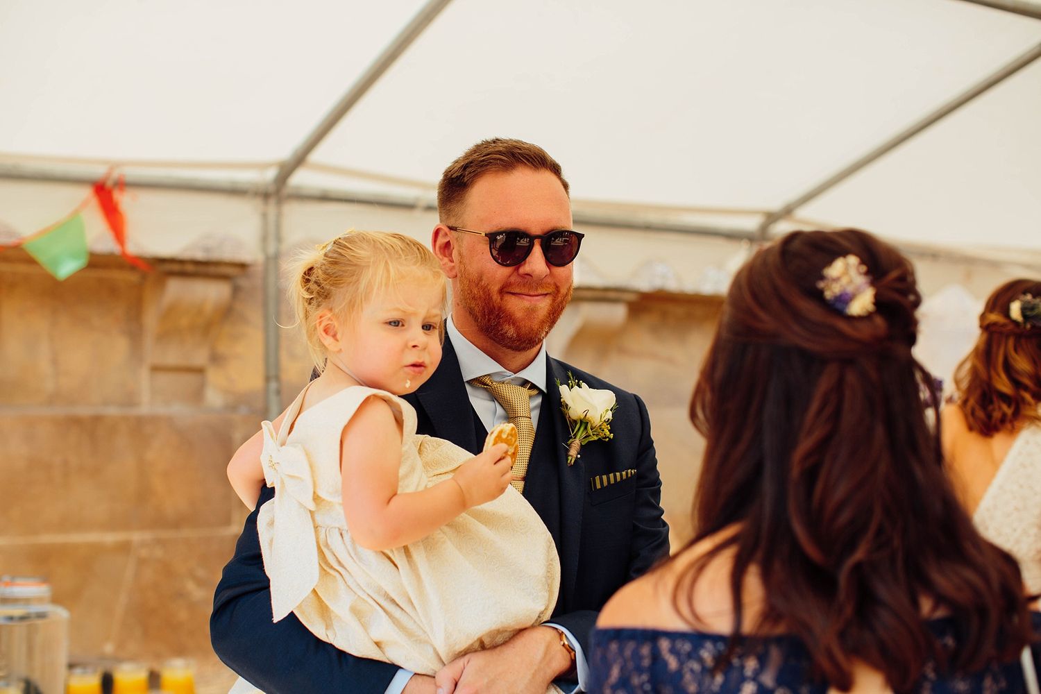 Wedding reception guests celebrate under white tent with festive atmosphere.