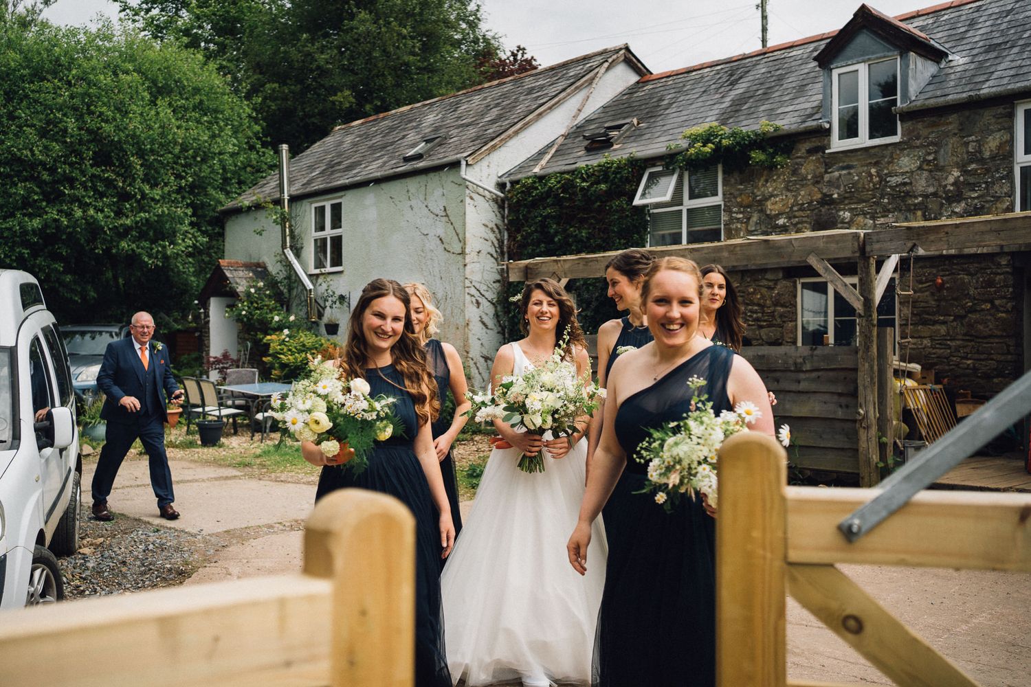 Guests gather for an outdoor wedding celebration at a rustic countryside venue.