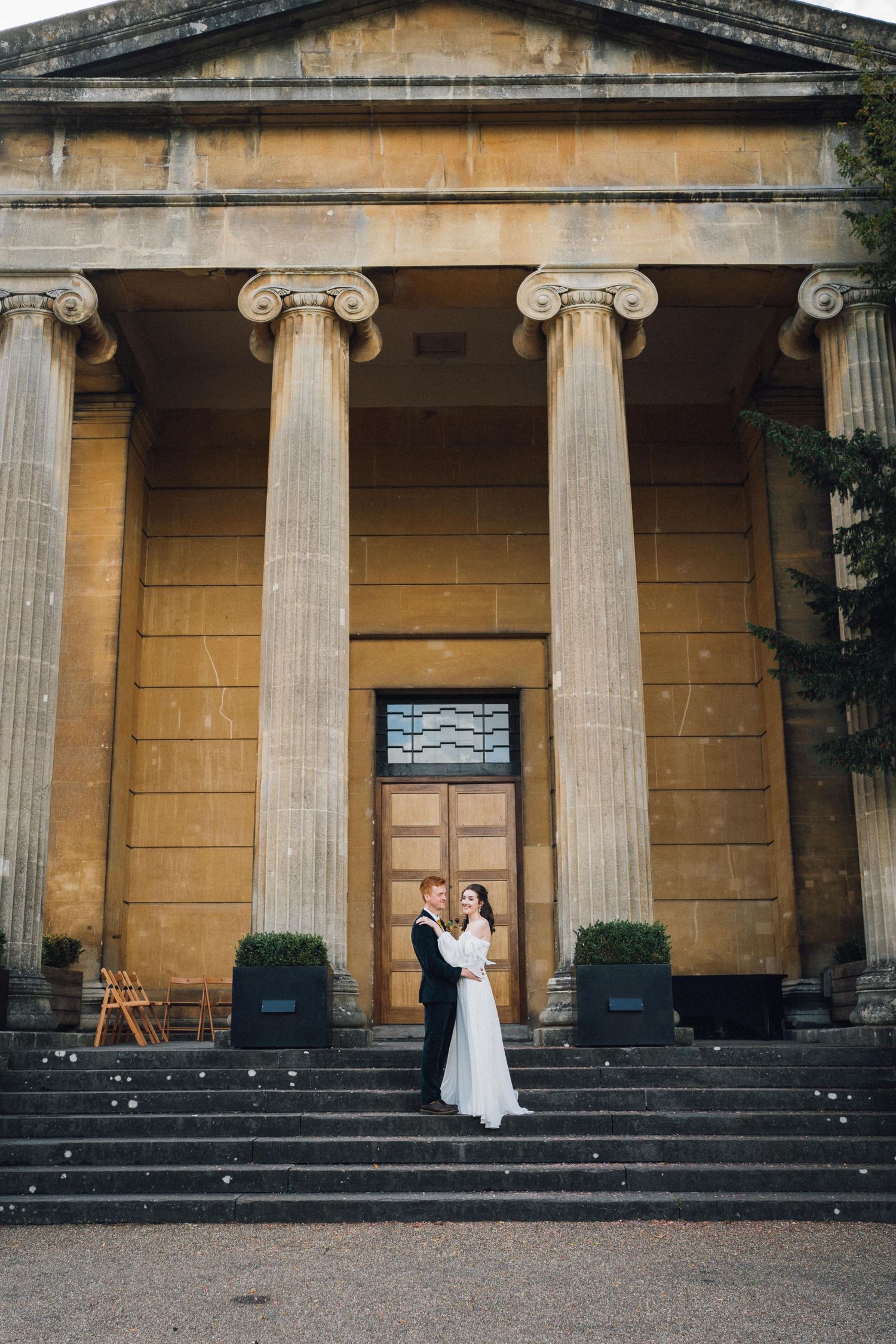 A wedding couple poses on grand stone steps with Ionic columns of a classical building in a sequence of progressive shots.