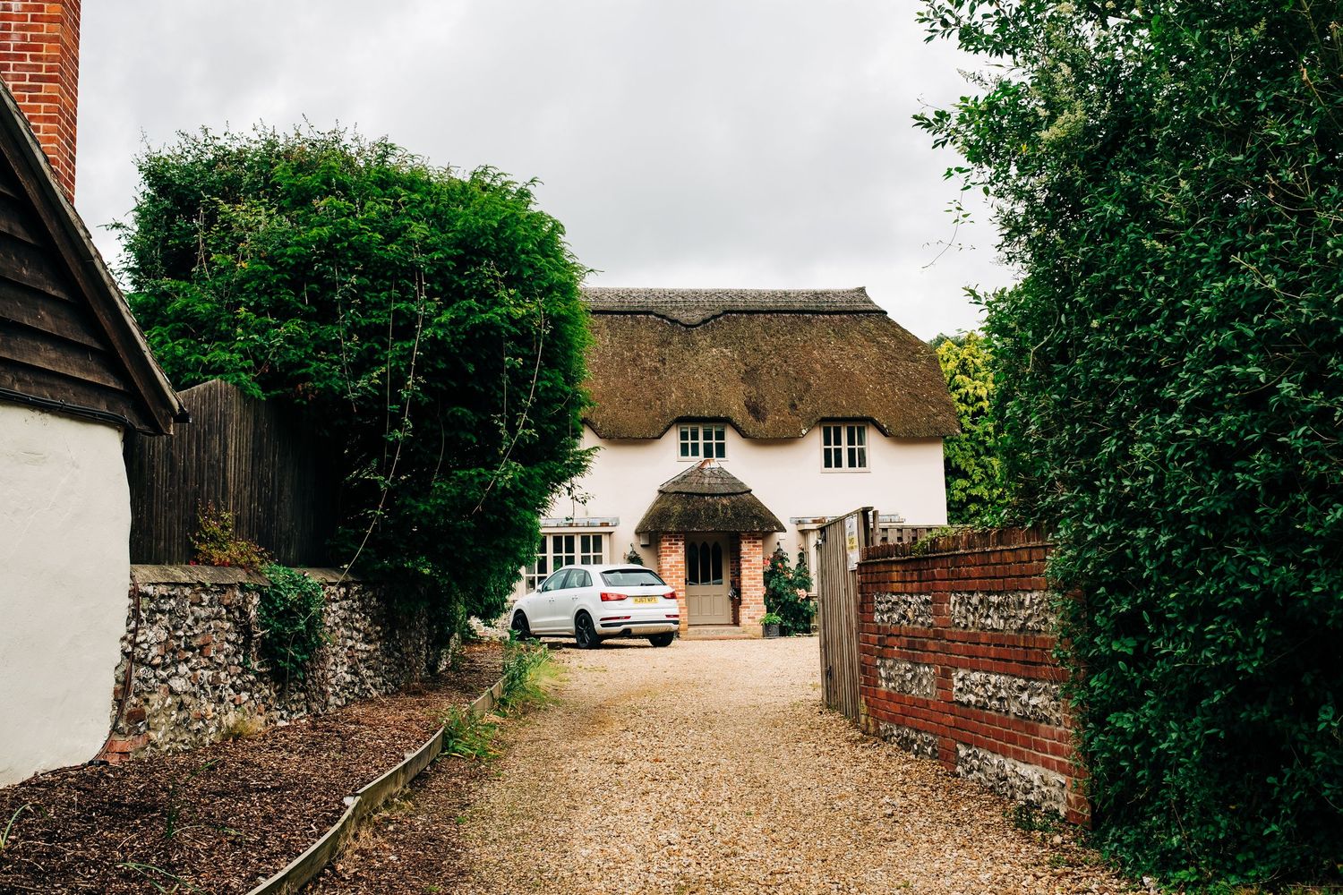 Rural countryside path with brick buildings and thatched roof cottages.
