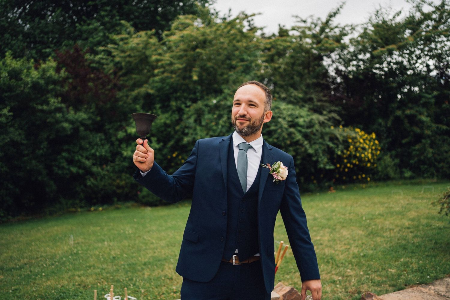 A person in formal attire playing lawn games at an outdoor wedding event.