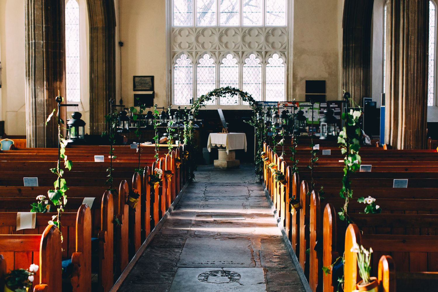 Sunlit church interior with wooden pews and stained glass windows creating a warm atmosphere.