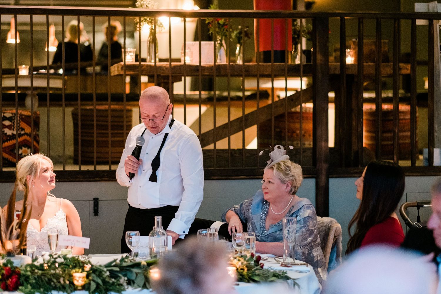 Wedding reception dinner scene with guests seated at decorated tables.