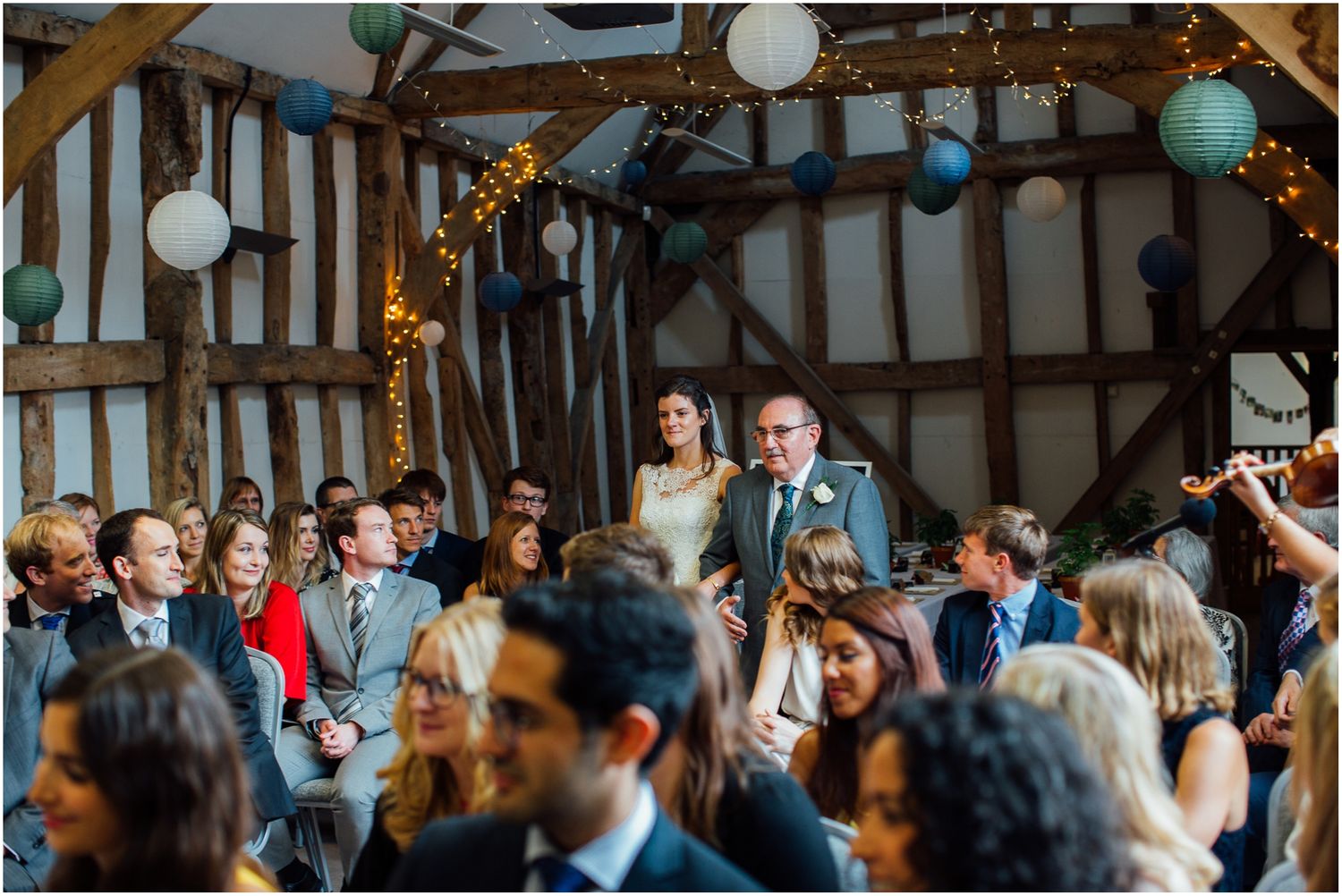 Wedding guests dancing and celebrating in a timber-framed reception hall.