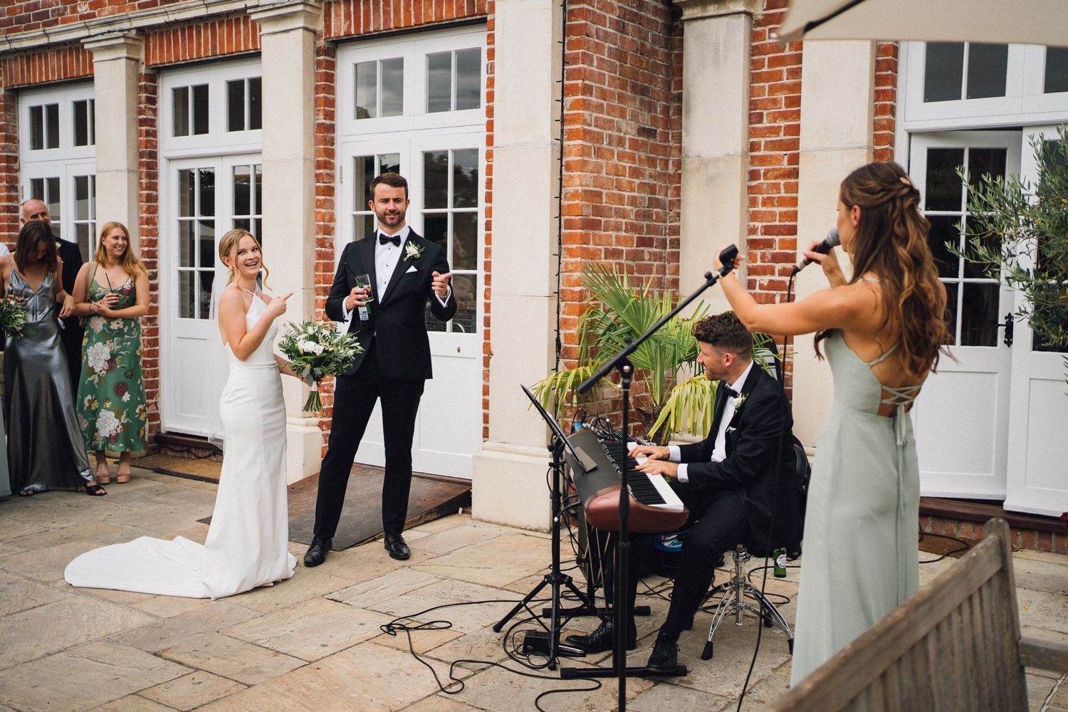 Guests gather for celebrations outside a classic brick building with white trim and columns.