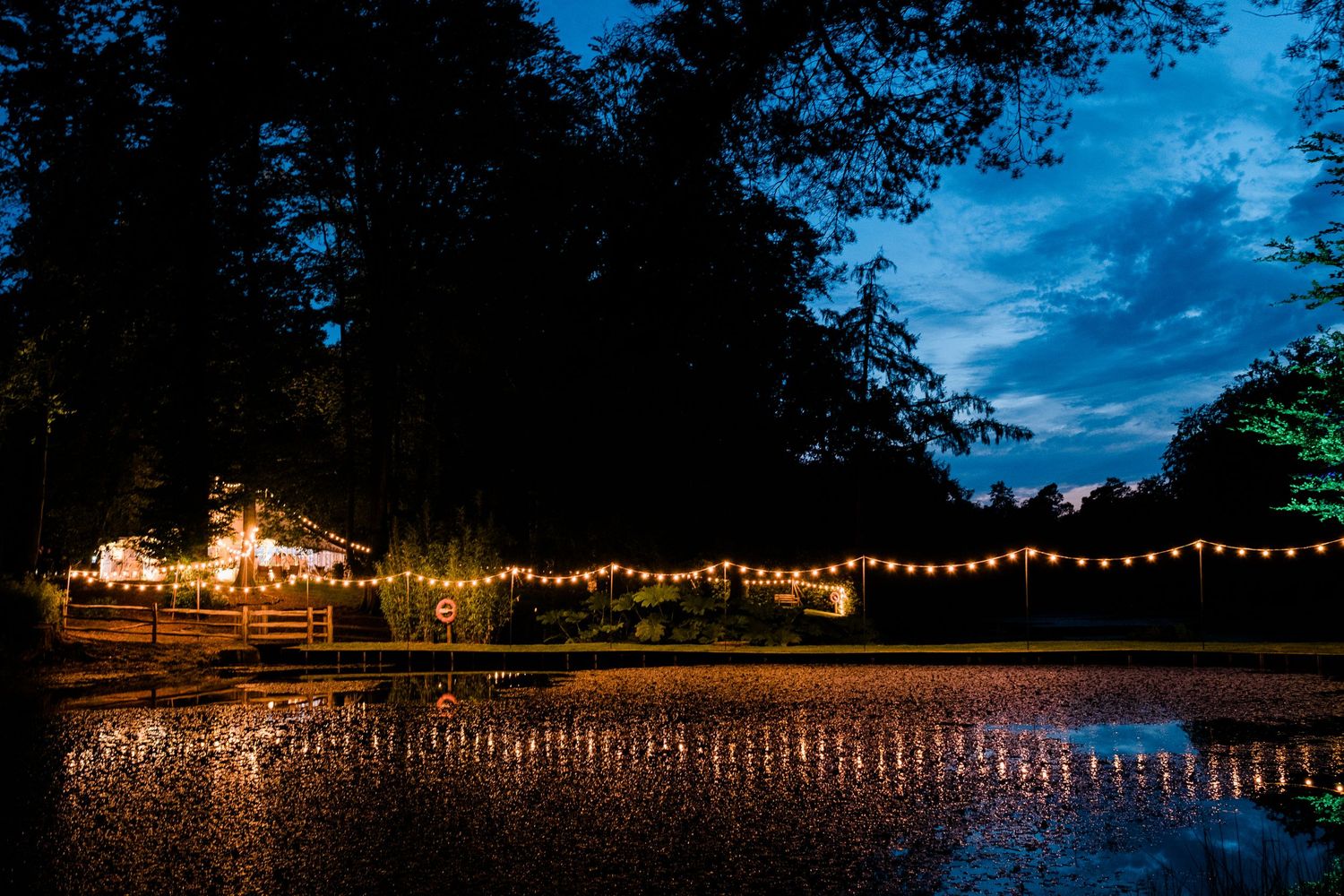 String lights create a magical ambiance over an outdoor wedding venue at twilight.