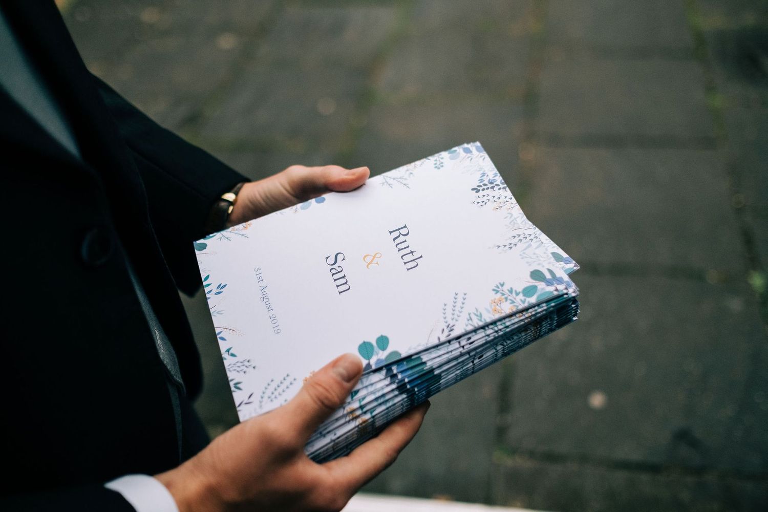 Close-up of hands holding wedding ceremony programs.
