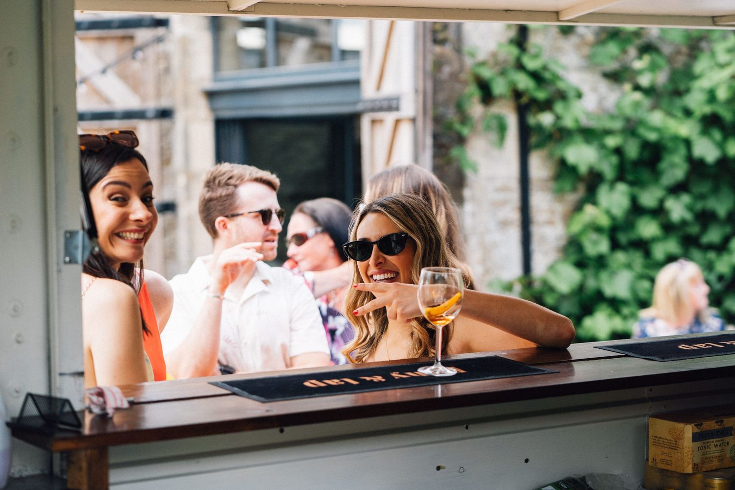 Wedding guests gather at an outdoor bar counter during a reception celebration.