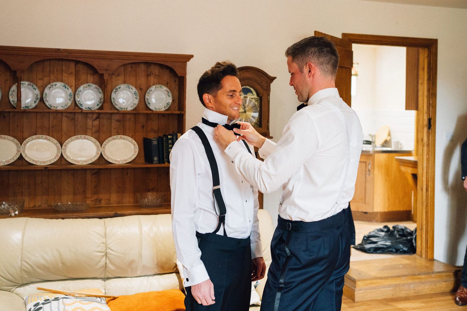 Wedding party getting ready in a rustic room with wooden furniture and decorative plates on display.