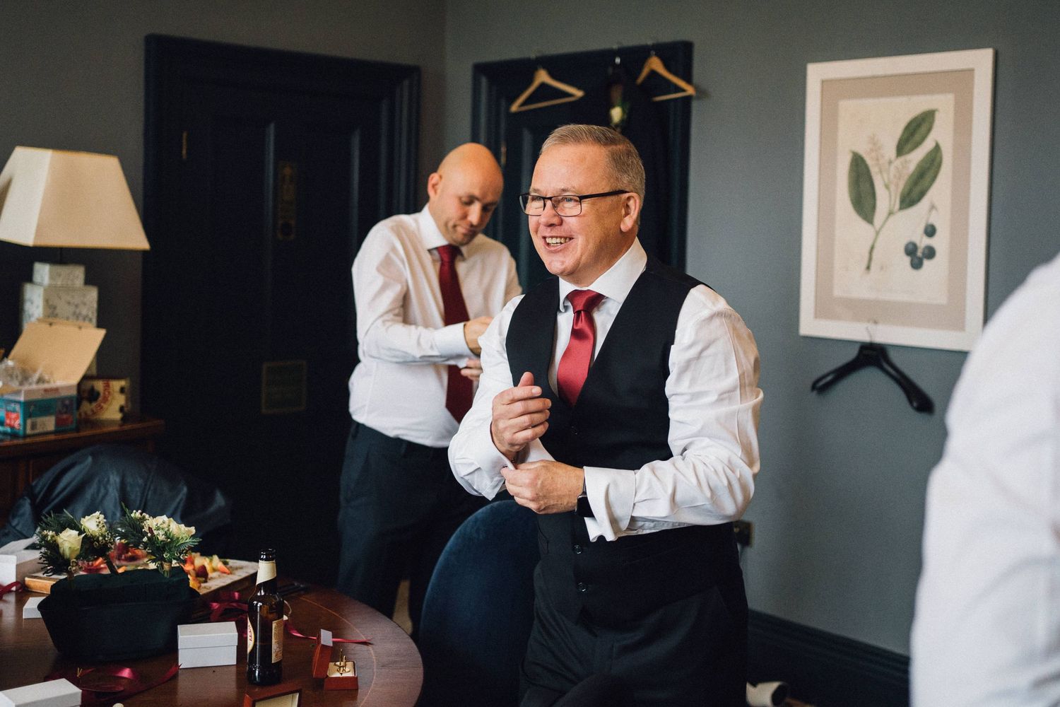 Wedding party preparations in a sophisticated room with botanical artwork and dark walls.
