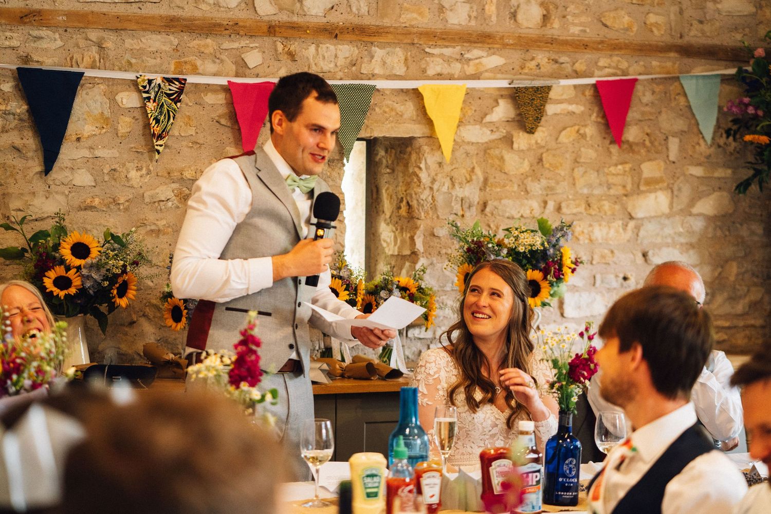 Wedding celebration in rustic venue with stone walls and colorful flag bunting decorations.