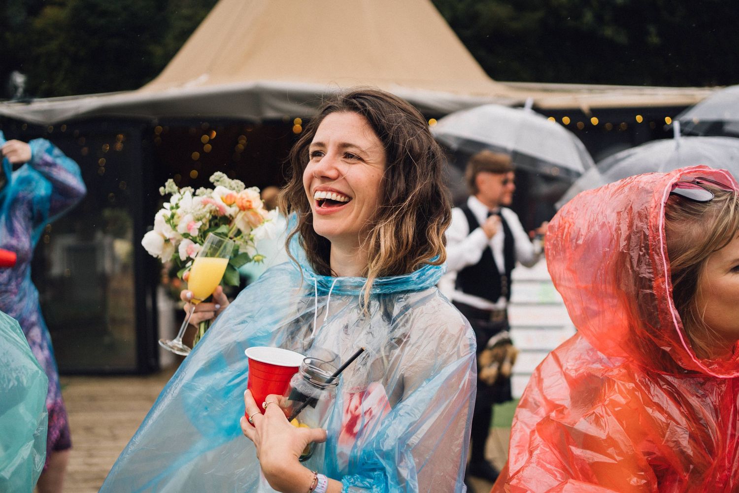 Group of people in colorful rain ponchos enjoying an outdoor event despite the rainy weather.