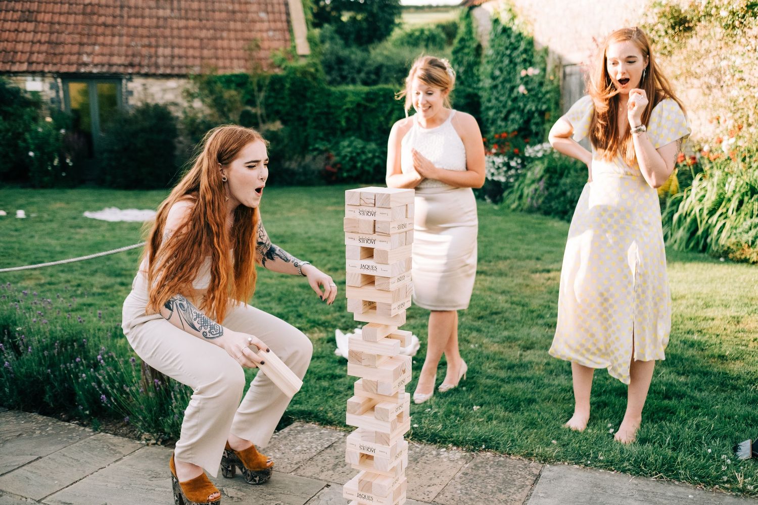 Wedding party playing oversized wooden block game on stone patio.