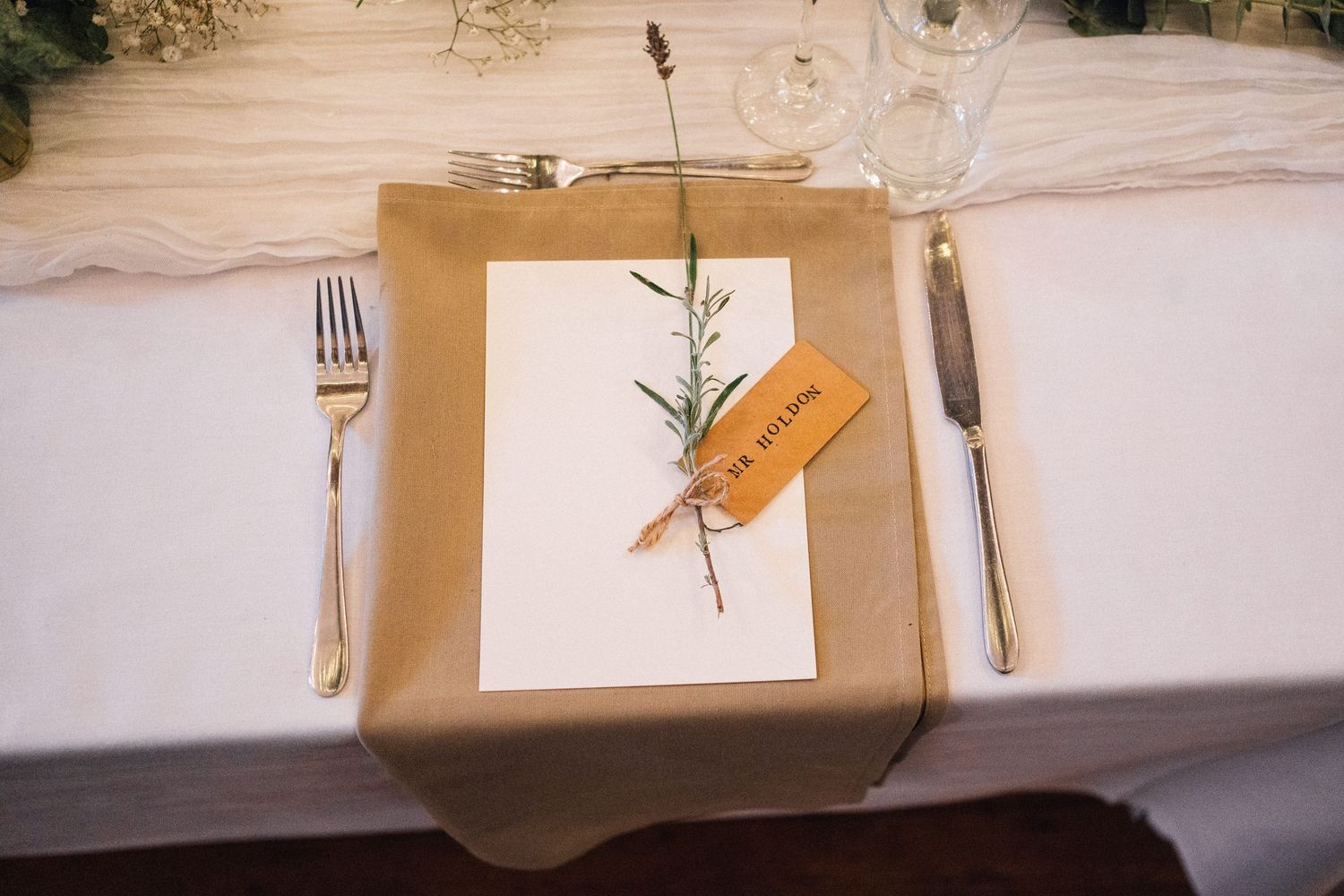 Elegant place settings with rustic details and natural elements on a white tablecloth.