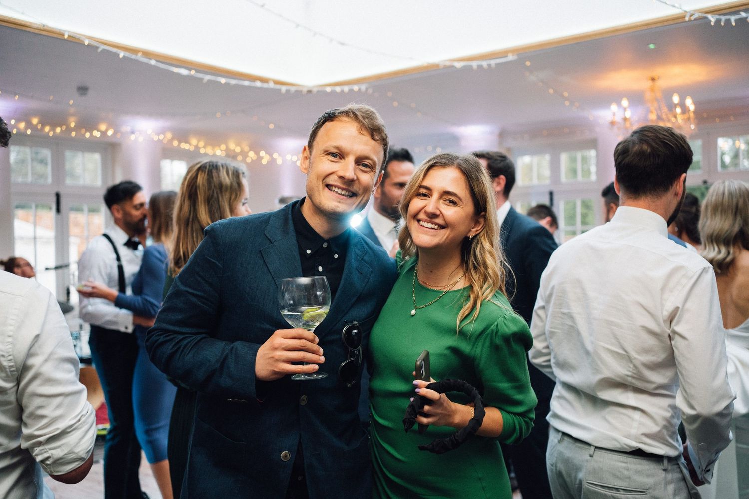 Wedding reception guests mingling and celebrating in an elegantly lit indoor venue.