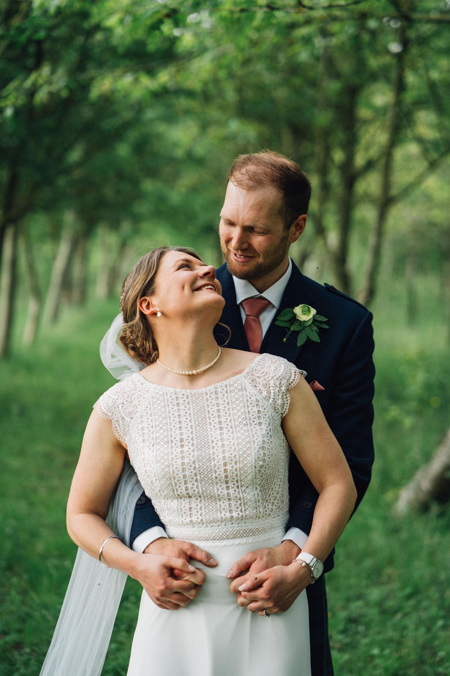 Couple embraces while laughing together during forest wedding photoshoot.
