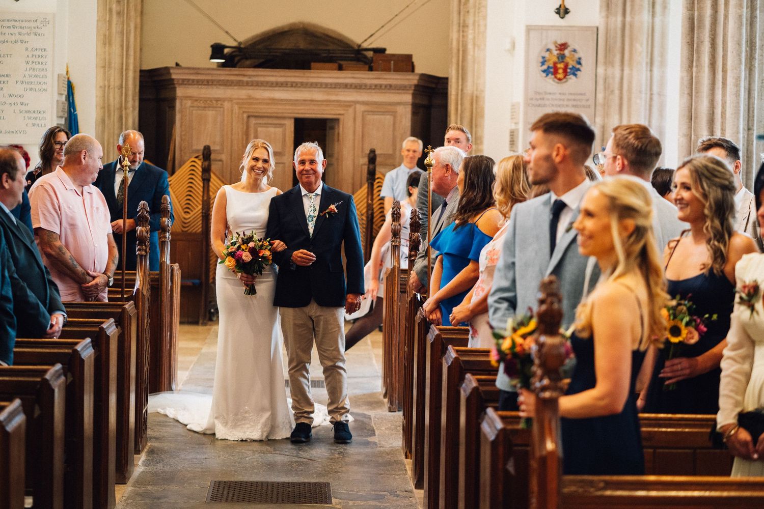 Wedding guests gather inside an elegant church with ornate architecture during a ceremony.