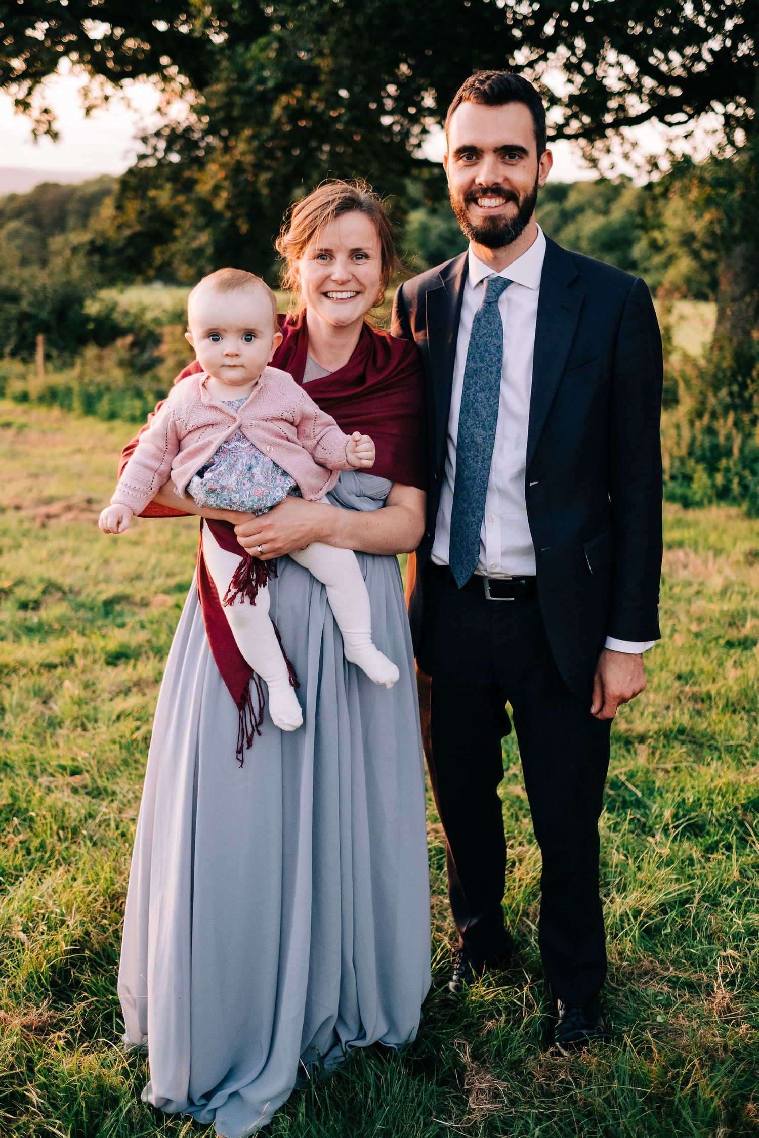 Family portrait in evening sunlight with baby wearing pink outfit.