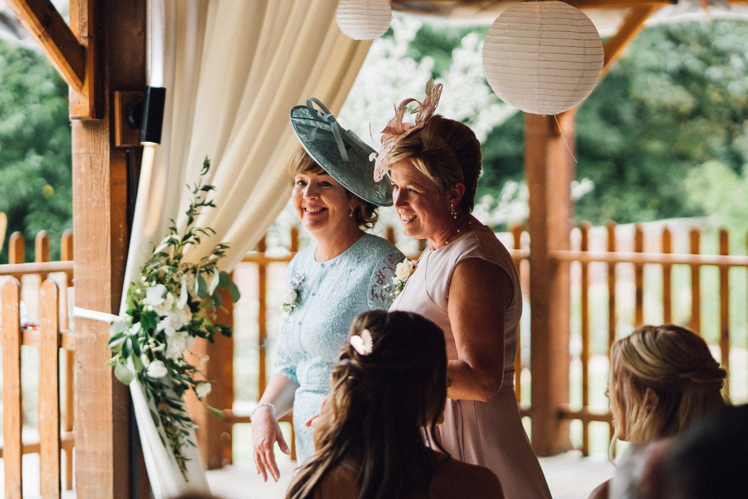 Wedding party gathered in an elegant barn venue decorated with white drapes and floral arrangements.